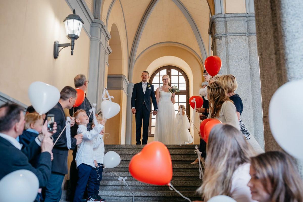 Braut und Bräutigam verlassen die Kirche unter Luftballons
