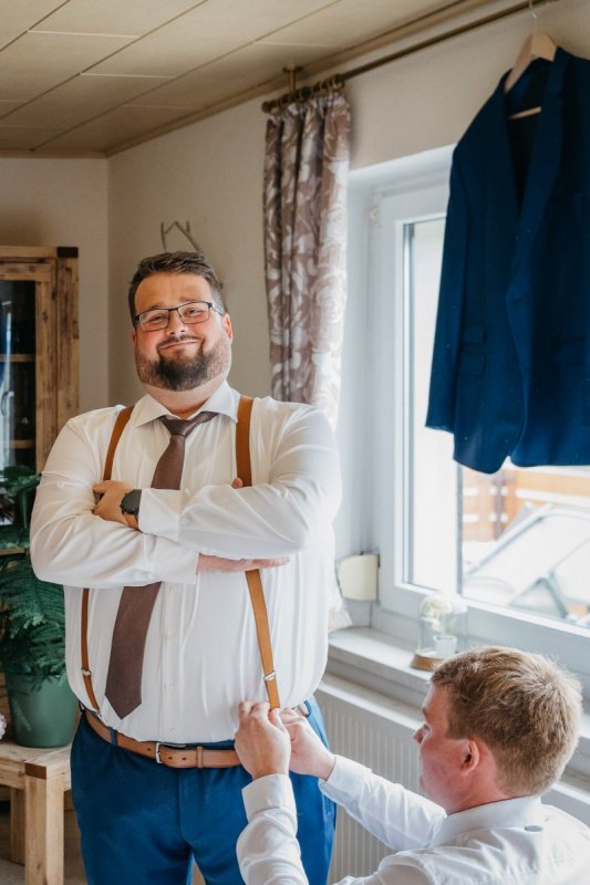 Tobias lächelt beim Getting Ready im Hochzeitsanzug