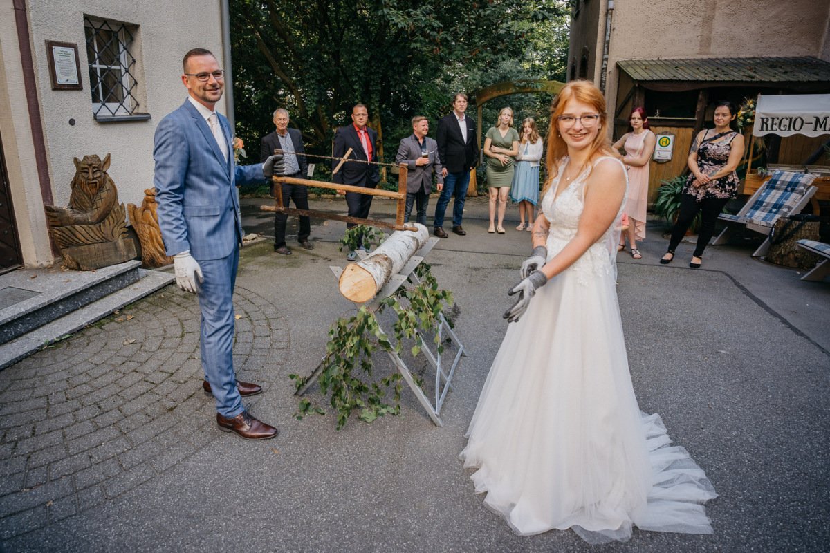 Linda und Robert sägen gemeinsam den Hochzeitsbaumstamm