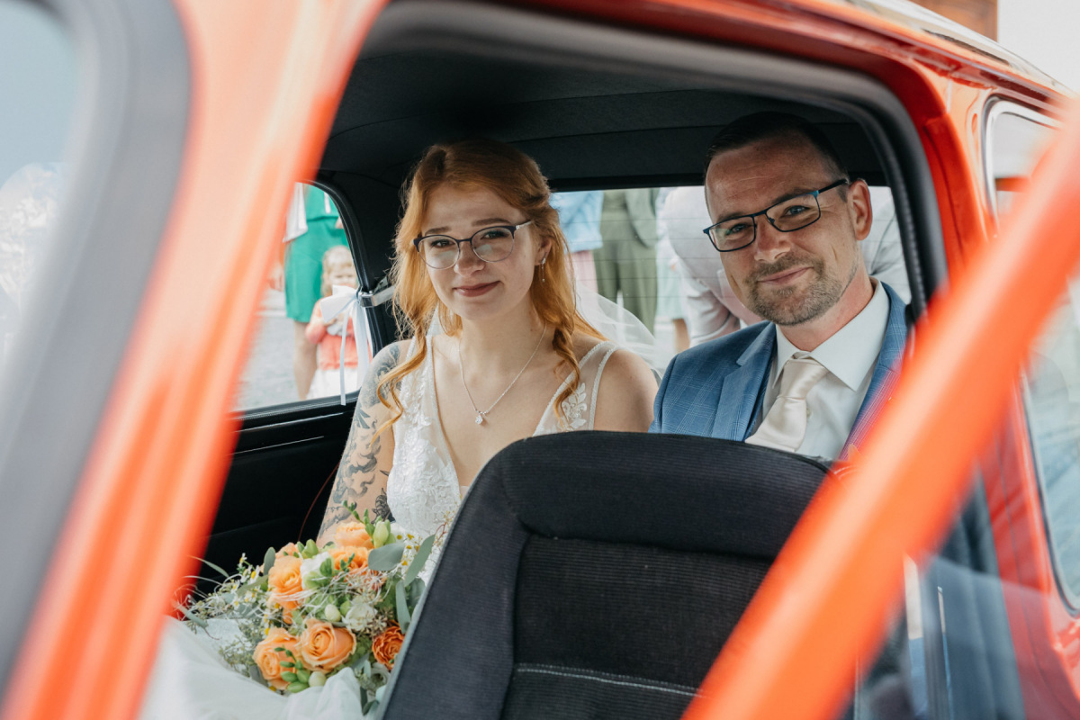 Linda und Robert fahren im roten Mini zur Hochzeitsfeier