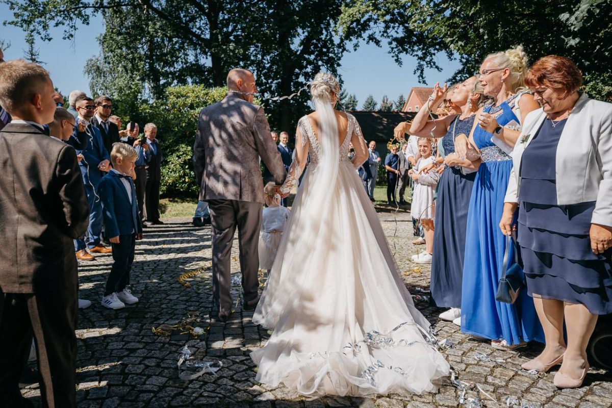 Braut und Bräutigam gehen durch ihre gratulierenden Gäste