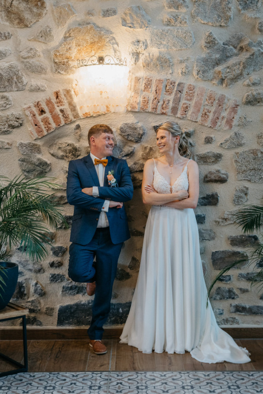 Sandra und Andy lachen beim Paarshooting vor einer Natursteinwand