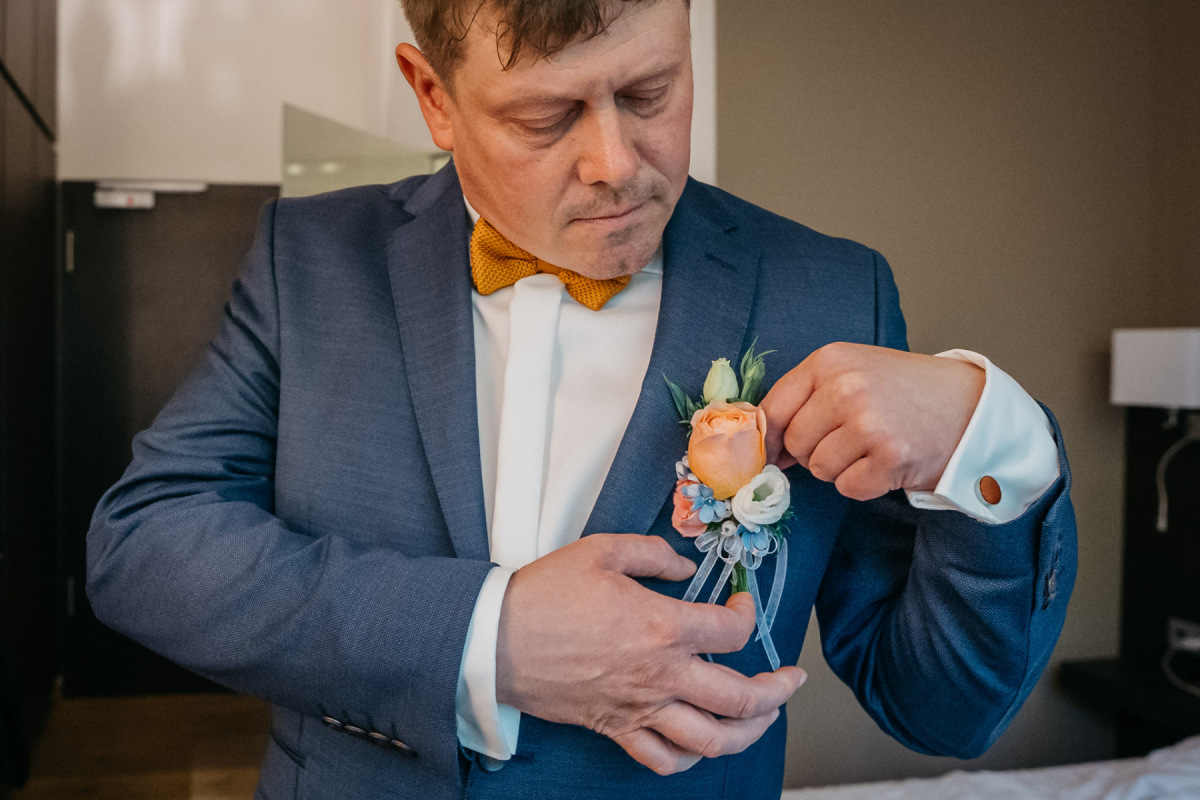 Andy befestigt seinen floralen Anstecker am Hochzeitsanzug